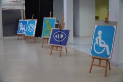 Plansze prezentujące różne rodzaje niepełnsprawności wyeksponowane na sztalugach na forum szkoły.