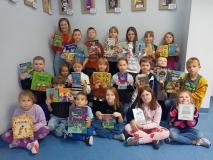Klasa 2 f wraz z wychowawczynią pozuje do grupowego zdjęcia pokazując okładki ulubionych książek.