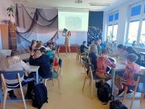 Klasa 4a uczestniczy w czytelni biblioteki w zajęciach „Baśniowe pudełko”, siedzą przy stołach i rozwiązują zadanie.