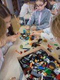 Uczestnicy warsztatów „LEGO w bibliotece – tu kwitnie wyobraźnia” konstruują budowle nawiązujące do kosmosu.