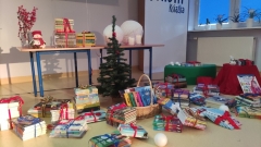 Świąteczna sceneria w bibliotece: kominek, bujany fotel, świeczniki, gałązki świerku, śnieżne kule, choinka z bombkami oraz nowe książki dla czytelników.