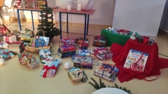 Świąteczna sceneria w bibliotece: kominek, bujany fotel, świeczniki, gałązki świerku, śnieżne kule, choinka z bombkami oraz nowe książki dla czytelników.