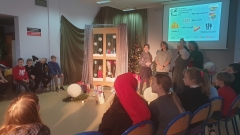 Na tle zimowej dekoracji wicedyrektor Agnieszka Gawlińska wraz z uczniami bawią się w "ciepło - zimno".