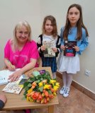 Dziewczynki pozują do zdjęcia z pisarką, trzymając otrzymane książki z autografem