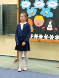 Na tle dekoracji dziewczynka recytuje przygotowany przez siebie utwór literacki.