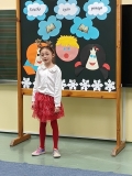 Na tle dekoracji dziewczynka recytuje przygotowany przez siebie utwór literacki.