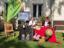 Dwoje uczniów w strojach z epoki siedzi za stołem i czyta fragmenty dramatu „Kordian” Juliusza Słowackiego podczas akcji Narodowego Czytania w ogrodzie Książnicy Płockiej.