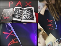 Dzieci rozwiązują zadanie wykorzystując plakat z napisem PAX w kolorze czerwonym umieszczonym na czarnym tle oraz książkę „PAX. Pal przekleństwa”. 