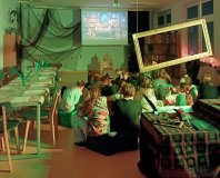 Grupa dzieci słucha wybranych fragmentów audiobooka „PAX. Pal przekleństwa” w bibliotece …