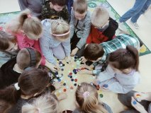 Uczniowie z korków od butelek układają na podłodze pierwszą literę swojego imienia.