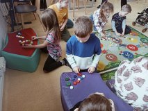 Uczniowie z korków od butelek układają na dywanie oraz na pufach pierwszą literę swojego imienia.