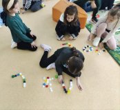 Uczniowie z korków od butelek układają na podłodze pierwszą literę swojego imienia.