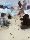 Uczniowie z wielkim zaangażowaniem z korków od butelek układają na podłodze pierwszą literę swojego imienia.