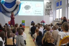 Uroczystość pasowania na czytelnika, grupa dzieci siedzi na podłodze, bibliotekarka prowadzi uroczystość.