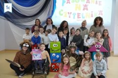 Zdjęcie grupowe klasy 1c, uczniowie pozują w galowych strojach, wokół nich figury zabawnych potworków.