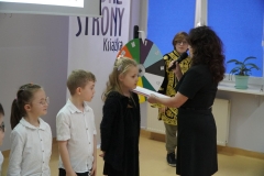 Dyrektor Agnieszka Gawlińska wielką księgą z bajkami dokonuje pasowania przedstawicieli pierwszaków na czytelników