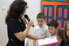 Dyrektor Agnieszka Gawlińska wielką księgą z bajkami dokonuje pasowania kolejnych przedstawicieli pierwszaków na czytelników