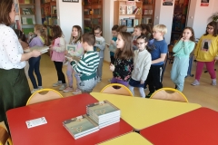 Nauczyciel bibliotekarz wręcza każdemu uczniowi klasy pierwszej wyprawkę czytelniczą