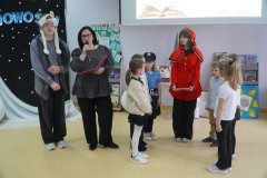 Pani wicedyrektor Iwona Kołodziejska, przedstawiciele klas pierwszych oraz pomocnicy z klas ósmych w przebraniu Czerwonego kapturka i wilka chwilę przed pasowaniem na czytelnika.
