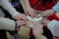 Ręce przedstawicieli uczniów klas na książce w czasie pasowania na czytelnika. 