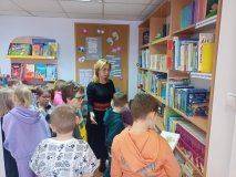 Uczniowie klasy pierwszej zapoznający się z księgozbiorem biblioteki w czasie lekcji bibliotecznej.  