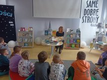  Pani Beata Szymczak, nauczycielka biblioteki, pokazująca uczniom klasy pierwszej ciekawe książki ze szkolnej biblioteki. 