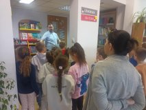 Pan Paweł Śmigała opowiadający uczniom klas pierwszych o książkach w kąciku dla najmłodszych.