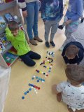 Pierwszoklasiści układający wyrazy z nakrętek plastikowych w czasie lekcji bibliotecznej. 