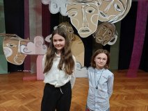 Ania i Zosia na tle teatralnej dekoracji podczas konkursu recytatorskiego w MDK. 