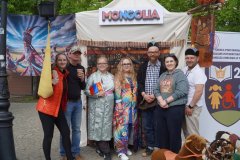 Grupa osób pozuje przed stoiskiem oznaczonym napisem „Mongolia”.
