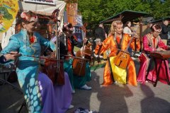 Muzycy w kolorowych tradycyjnych strojach prezentują występ instrumentalny na świeżym powietrzu