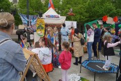 Dzieci i dorośli odwiedzają stoisko Mongolii podczas wydarzenia plenerowego; dzieci bawią się przy małej trampolinie.