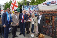 Grupa osób pozuje przy stoisku Mongolii, trzymając flagi Mongolii i Gruzji.