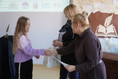 Dyrektor Szkoły Podstawowej nr 22 i przewodnicząca jury wręczają dziewczynce dyplom i torbę z logo konkursu