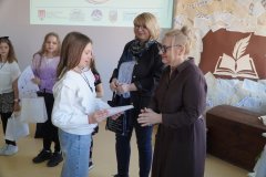 Dyrektor Szkoły Podstawowej nr 22 i przewodnicząca jury wręczają dziewczynce dyplom, w tle widać innych laureatów