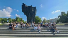 Grupa uczniów na schodach przy pomniku Władysława Broniewskiego podczas gry miejskiej „Z nich Płock jest dumny”.