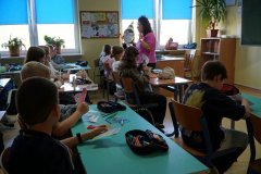 Sala lekcyjna. Uczniowie klasy czwartej siedząc w ławkach, słuchają realizatora zajęć profilaktycznych, P. Kingi Strąk. Trzymają w rękach własnoręcznie wykonane serca z papieru.