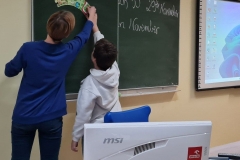 Nauczyciel i uiczeń wspólnie przyczepiają na tablicy puzzle nz nazwami miesięcy w języku polskim.