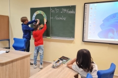 Nauczyciel i uczeń przyczepiają na tablicy kolorowe elementy puzzli.