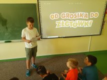 Uczeń odczytuje założenia programu, w tle napis "Od grosika do złotówki".