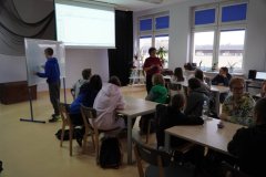 Uczniowie siedzący w ławkach i uczestniczący w zajęciach profilaktycznych.