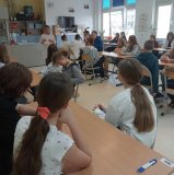 Uczniowie słuchający pogadanki pani nauczycielki na temat Marii Skłodowskiej-Curie.