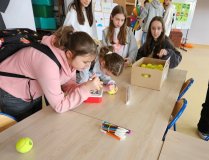 Uczniowie wykonują prace recyklingowe - emotki z piłek od tenisa.