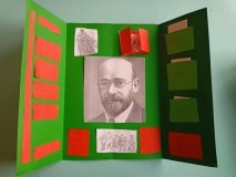 lapbook w kolorze zielonym, na nim przyklejone czerwone zakładki i czarnobiały portret patrona szkoły