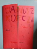 czerwony złożony lapbook , na którym widnieje kolorowy napis „Janusz Korczak – lekarz, pedagog, przyjaciel dzieci”