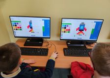 Grupa dzieci na komputerach układa obrazki na macie do kodowania