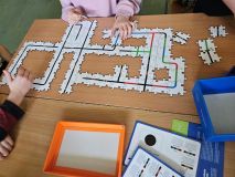 Pojedynczy kawałek układanki - puzzle do obozotów - leży na stole, trzymany przez dłoń, gotowy do umieszczenia w całości.