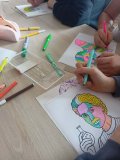 blat stołu, dłonie uczniów i kolorowe portrety Skłodowskiej w stylu popart