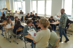 pracownia szkolna, uczniowie pogrupowani w zespoły dwu/trzy osobowe biorą udział w konkursie wiedzy, który prowadzi dwoje nauczycieli – kobieta i mężczyzna