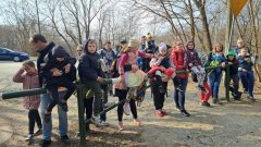 Grupa dzieci siedzących na leśnym szlabanie. W tle bezlistne drzewa.